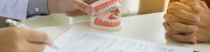 Dentist holding dentures signing contract