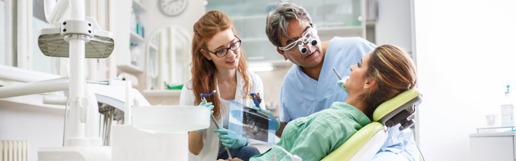 Dentist and Team Working with female patient in office
