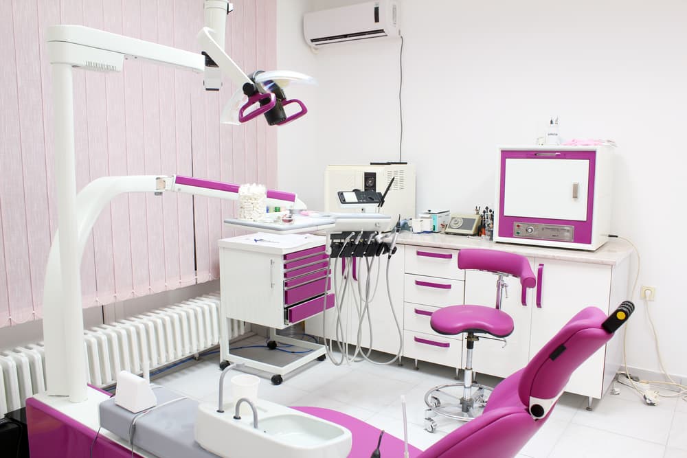 Experience a modern dental practice with pink-themed chairs and necessary instruments.