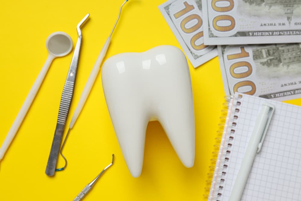 Creating a visual composition with dental tools, money, a decorative tooth, and a notepad on a yellow background can be both eye-catching and thematic, ideal for social media posts, promotional materials, or presentations.
