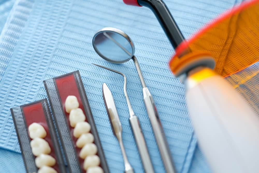 Dental instruments and dentures placed on a sterile medical napkin in a clinic, close-up view.