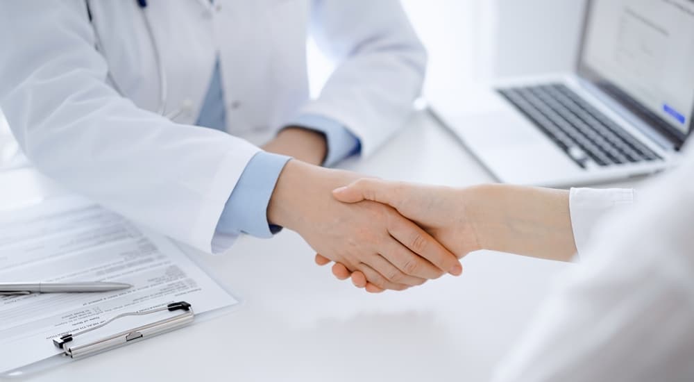 Doctor handshake and partnership in dental practice, fostering trust, collaboration, and unity in medicine.