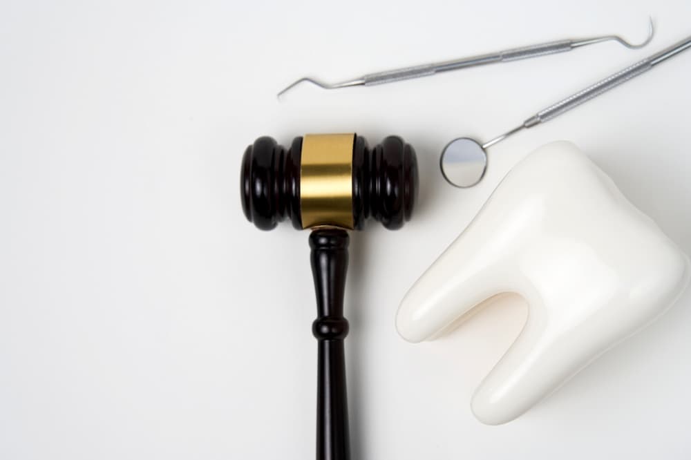 White tooth and judge gavel on white background