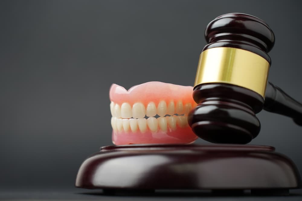 White tooth and judge gavel on black background