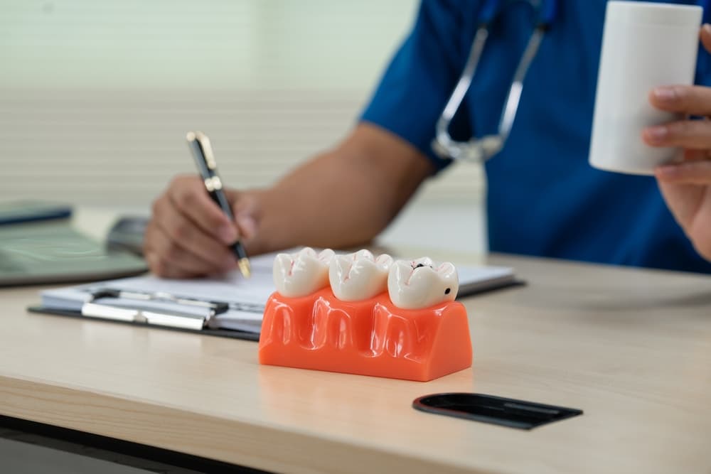 A male doctor sits working at the table in a dentist's clinic, explaining tooth decay, wisdom teeth.