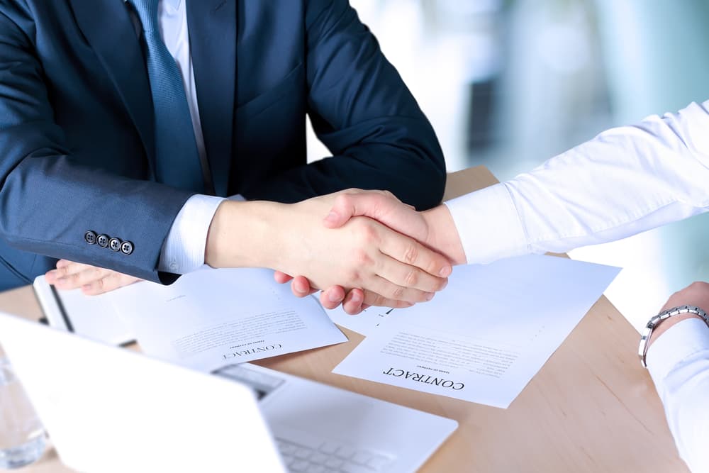 Close-up image of a firm handshake between two colleagues, symbolizing agreement and trust after signing a contract.