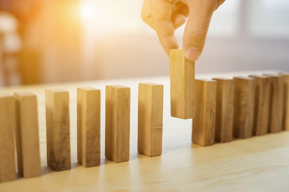 Close-up of a man's hand selecting a single wooden block from a collection, symbolizing decision-making in business strategy and risk management, with a vintage color tone.