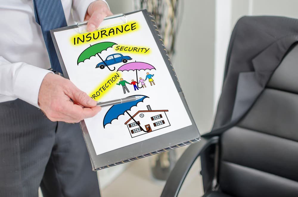 Businessman holding and displaying a clipboard with an insurance concept, showcasing various protection and policy icons, symbolizing business coverage options.