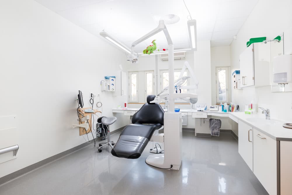 Interior of a modern dental practice featuring a dental chair and various dental tools and accessories, creating a clean and professional clinical setting.