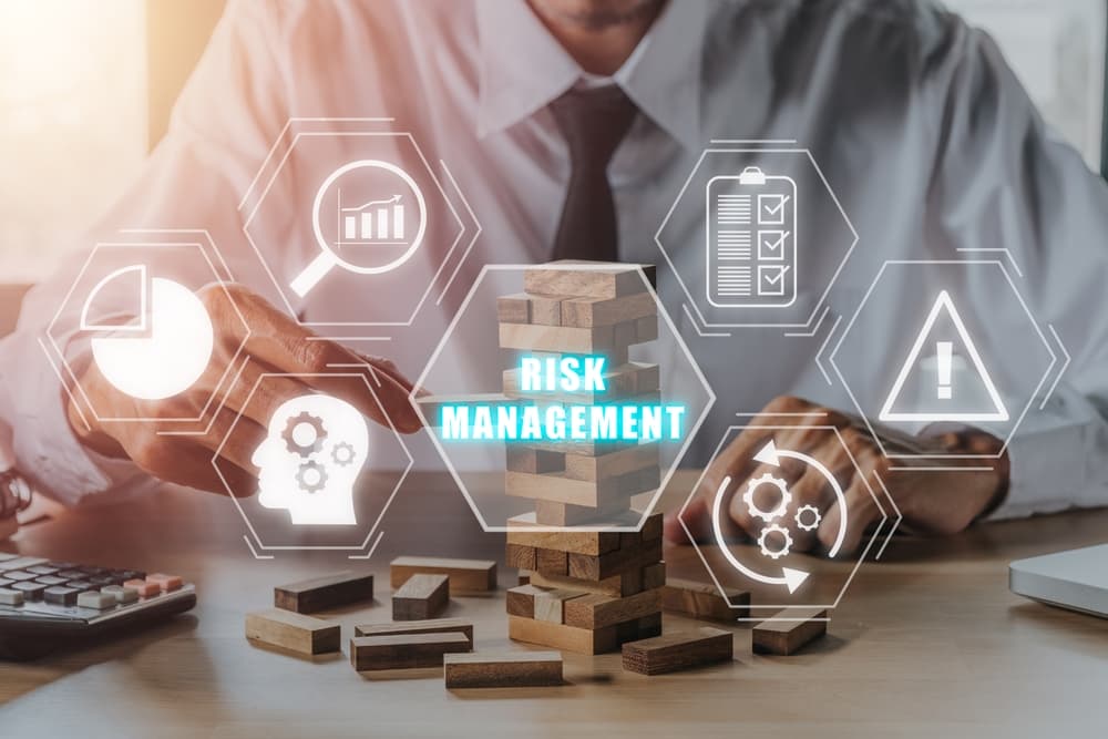 Person's hand stacking wooden blocks with risk management icons, representing a strategy plan for finance, investment, and technology in an internet business context.