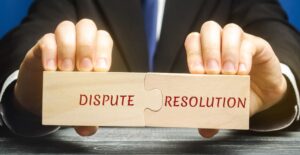 Man holds wooden puzzles with the words Dispute Resolution.