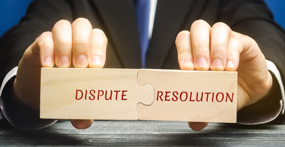 Man holds wooden puzzles with the words Dispute Resolution.