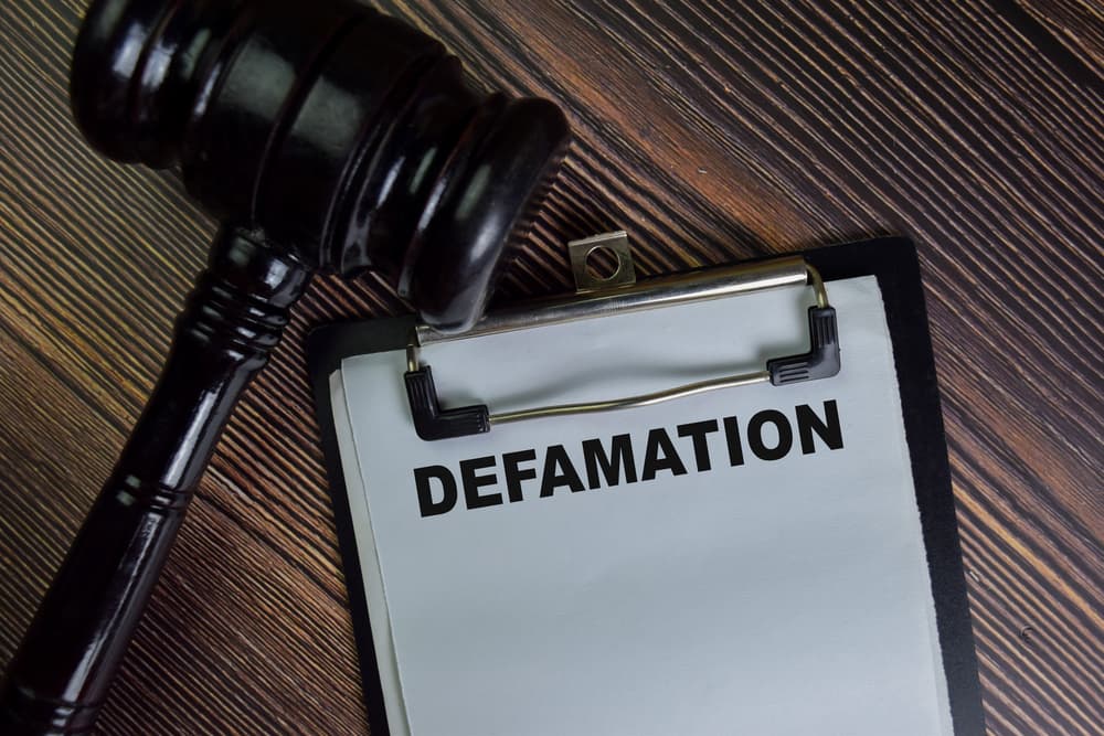 Defamation write on a paperwork isolated on Wooden Table.