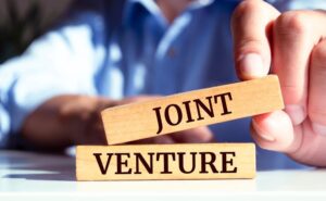 Close up on businessman holding a wooden block with "JOINT VENTURE" message