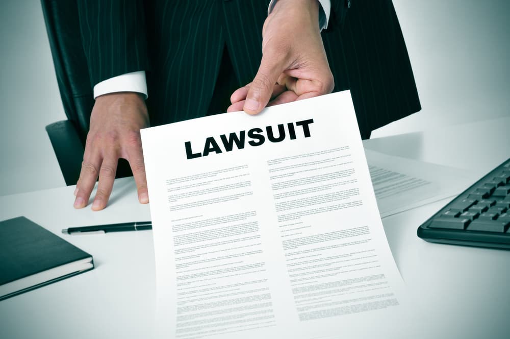A lawyer in his office showing a document with the text lawsuit written in it