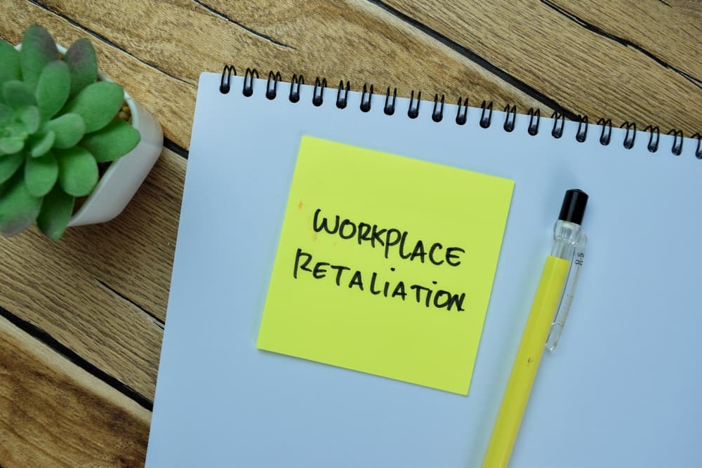 Workplace Retaliation write on sticky notes isolated on Wooden Table.