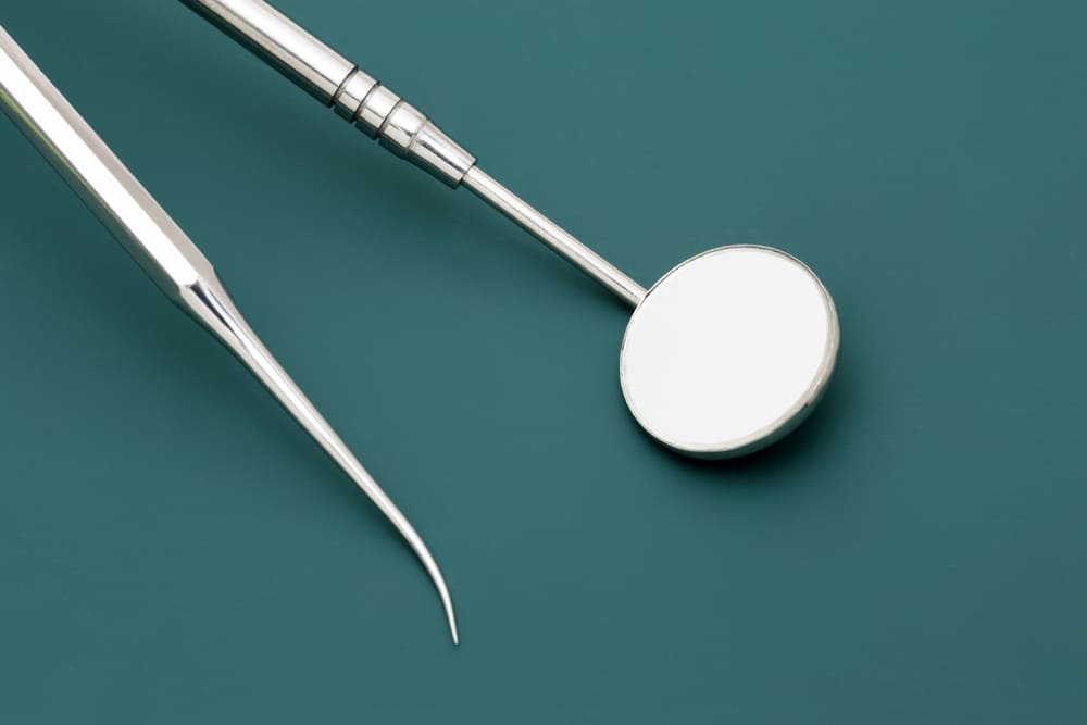 Close-up of dental mirror and explorer tools on a tray, representing standard equipment used in a dental practice