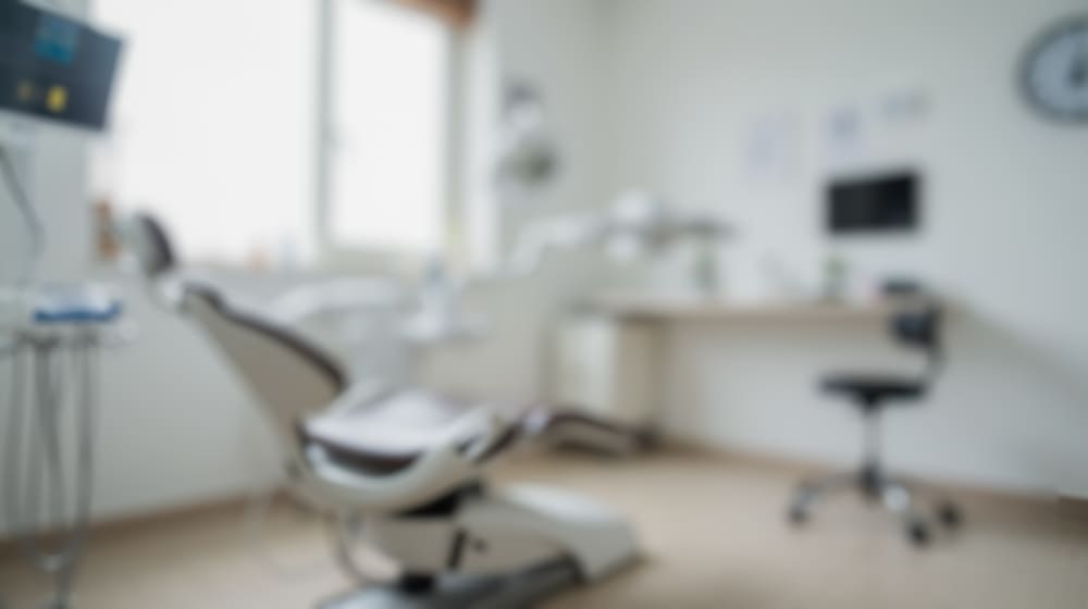 Blurred view of a modern dental operatory, representing a shared clinic space used by multiple dentists.